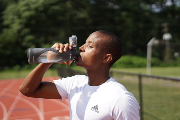 Young man drinking water after exercise